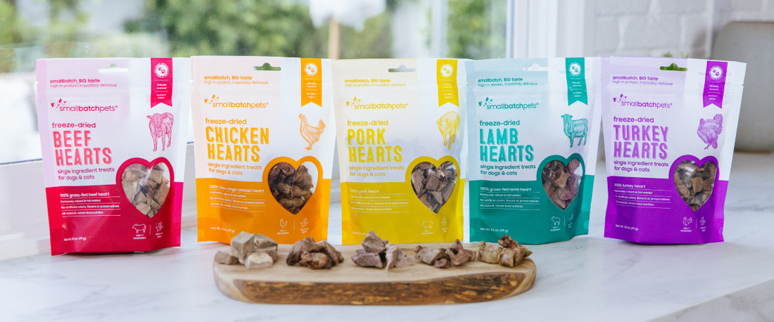 Assorted bags of Smallbatch freeze-dried heart treats for dogs and cats displayed with treats in front.