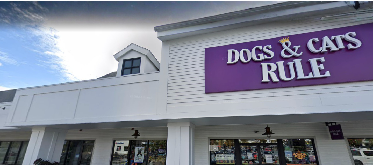 Storefront with a sign reading 'DOGS & CATS RULE' on a clear day.