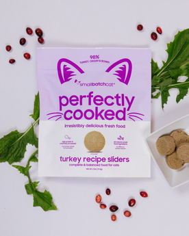 Smallbatch turkey perfectly cooked cat food package next to sliders and ingredients.