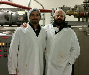 Two men standing in production facility in food safe outfits. 