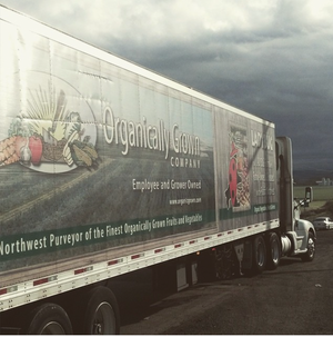 Truck that says "Organically Grown Company" driving near farmland.