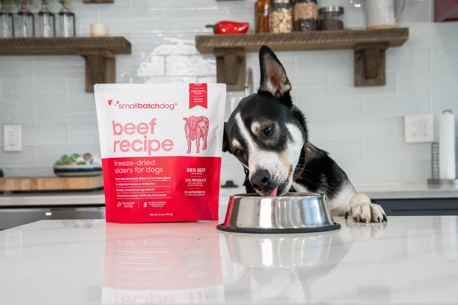 Dog eating out of bowl on counter next to smallbatch freeze-dried sliders package.